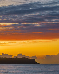 Sunrise and colourful high cloud over the sea and headland