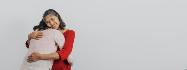 Obraz premium hug with love, Senior mature asian woman with young daughter sitting together on couch, giving hug and love feeling happy, Mother day, birthday, family anniversary, love mom concept.