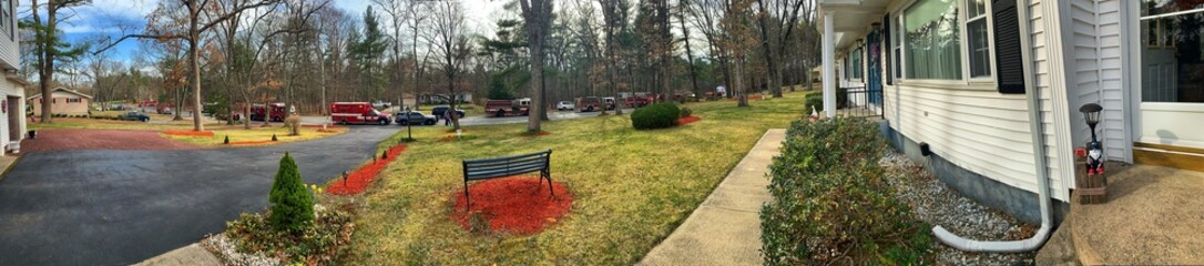 Panoramic View of Firetruck and Rescue Vehicles Lining the Street Closed due to a House & Tree Fire in the Woods