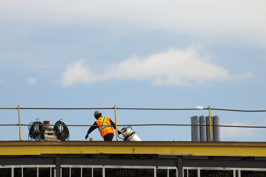 construction worker roofer carrying propane torch and gas tank to repair flat roof