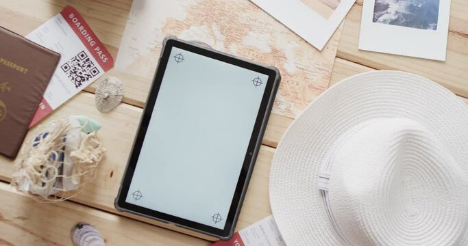 Flat lay of tablet with copy space, passport and sunhat on wooden background