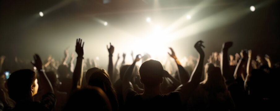 A crowd of people at a live event, concert or party hands in the air. Large audience, crowd, or participants of a live event, in a concert hall type venue with bright lights above. Generative AI.