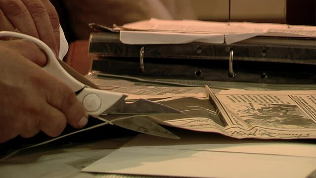 Man Cutting A Newspaper While Storing Clippings Of Chamame Folk Music Articles In Argentina. Close Up.