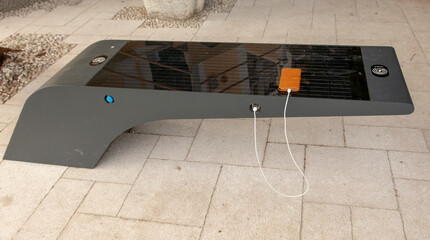 Smart Solar Bench in public place,  powered by sunlight provides wireless and wired charging for users.