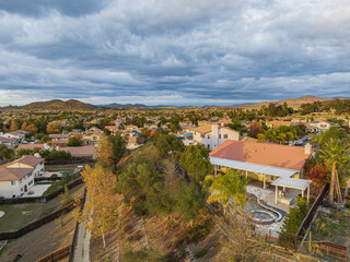 Obraz premium Aerial view of backyard with pool on a cul de sac street surrounded by luxury single family homes rolling hills in new residential West Coast USA real estate suburban neighborhood dramatic sunset sky