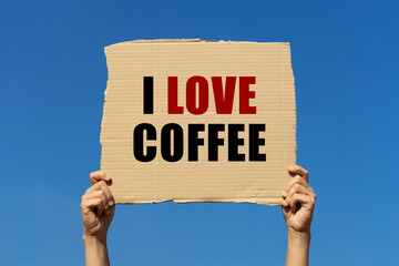I love coffee text on box paper held by 2 hands with isolated blue sky background. This message board can be used as business concept about loving coffee.