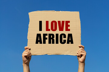 I love Africa text on box paper held by 2 hands with isolated blue sky background. This message...