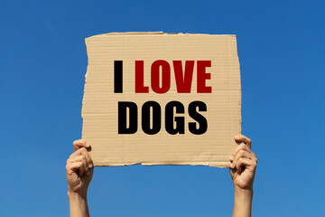 I love dogs text on box paper held by 2 hands with isolated blue sky background. This message board...