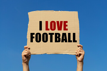 I love football text on box paper held by 2 hands with isolated blue sky background. This message board can be used as business concept about football.
