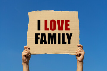 I love family text on box paper held by 2 hands with isolated blue sky background. This message...