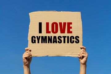 I love gymnastics text on box paper held by 2 hands with isolated blue sky background. This message board can be used as business concept about your gymnastics.