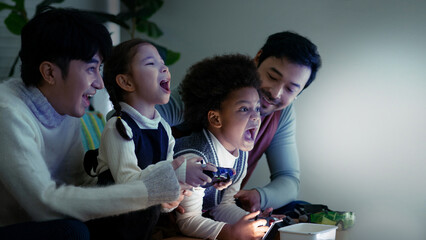 Male gay couple having fun with kids playing video game console, LGBTQ family concept