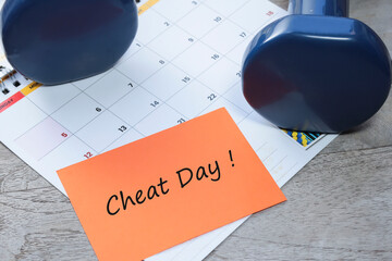 The cheat Day message was written on a piece of paper on the calendar with the dumbbell at the side 