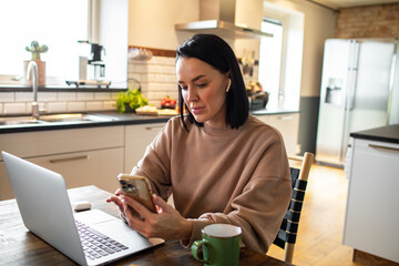 Young adult woman using her phone at home
