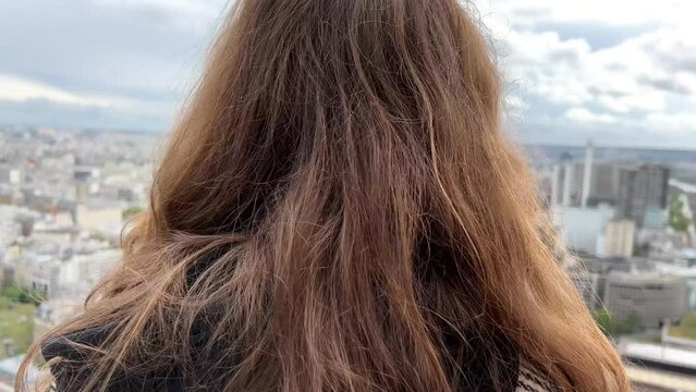 A girl on a eiffel tower looks around at the city of Paris visible houses the Seine River with boats and the city 06.04.22 Paris France center. High quality 4k footage