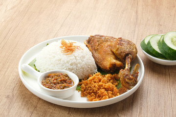 Bebek Goreng Kremes, served with chili sauce (sambal) and cucumber. Indonesian food
