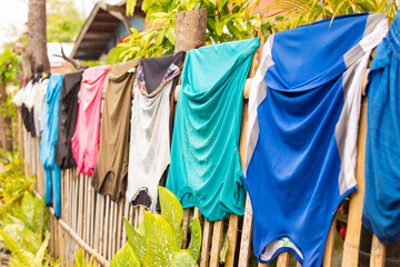 Clothes of different colors are drying on the bamboo fence
