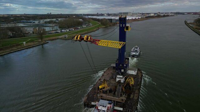 Cargo crane transport ship navigating through the canal on a cloudy day in Zwijndrecht, The Netherlands.