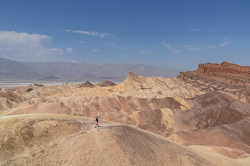 Man with scenic view of summit peak Manly Beacon seen from Zabriskie Point, Badlands, Furnace...