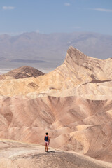 Man with scenic view of summit peak Manly Beacon seen from Zabriskie Point, Badlands, Furnace...