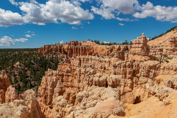 Fototapeta premium Panoramic aerial view on massive hoodoo sandstone rock formation towers in Bryce Canyon National Park, Utah, USA. Pine trees along Fairyland loop hiking trail. Unique nature in barren landscape
