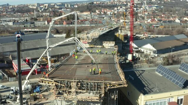 Workers preparing crane cement pumps at city bridge construction site.
