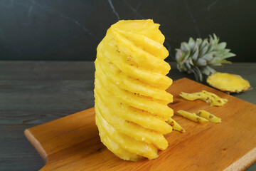 Peeled and nicely cut fresh ripe pineapple on a wooden cutting board
