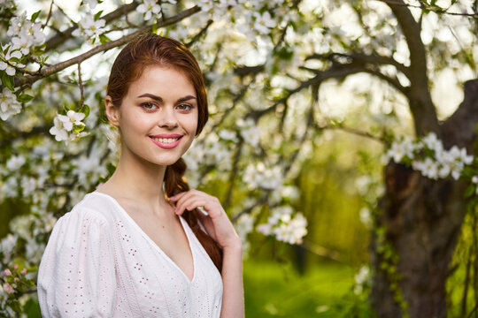 Beautiful young woman. model in white dress stands in white flowers. Horizontal photo. copy space.