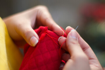 Close up of mom hands sewing a sweater, fix not throw