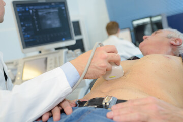 doctor using ultrasound scan on abdomen of senior male patient