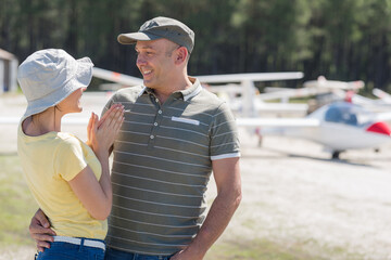 cheerful young couple hugging and laughing near private plane