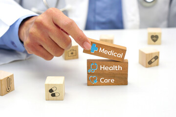 Hand of doctor holding a wooden block cube with text and behind it is a wooden block with blurred icon symbol. Medical and health concept.