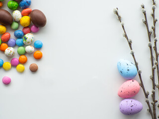 Sweet Easter concept. Colorful and chocolate easter eggs with sweet dragee on white background with copy space. Design for a greeting card for the Easter holiday. Flat lay. Preparation for holiday.
