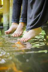 feet of lovers playing in the fish pond
