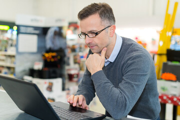 man wearing spectacles using laptop in store