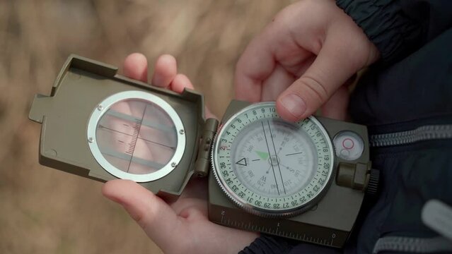 Close-up of a child's hands holding a magnetic compass for navigation. Little traveler learns to find his location as well as the direction of movement. Travel and active lifestyle concept.