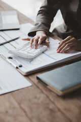 Businessman using a calculator to calculate numbers on a company's financial documents, she is analyzing historical financial data to plan how to grow the company. Financial concept.