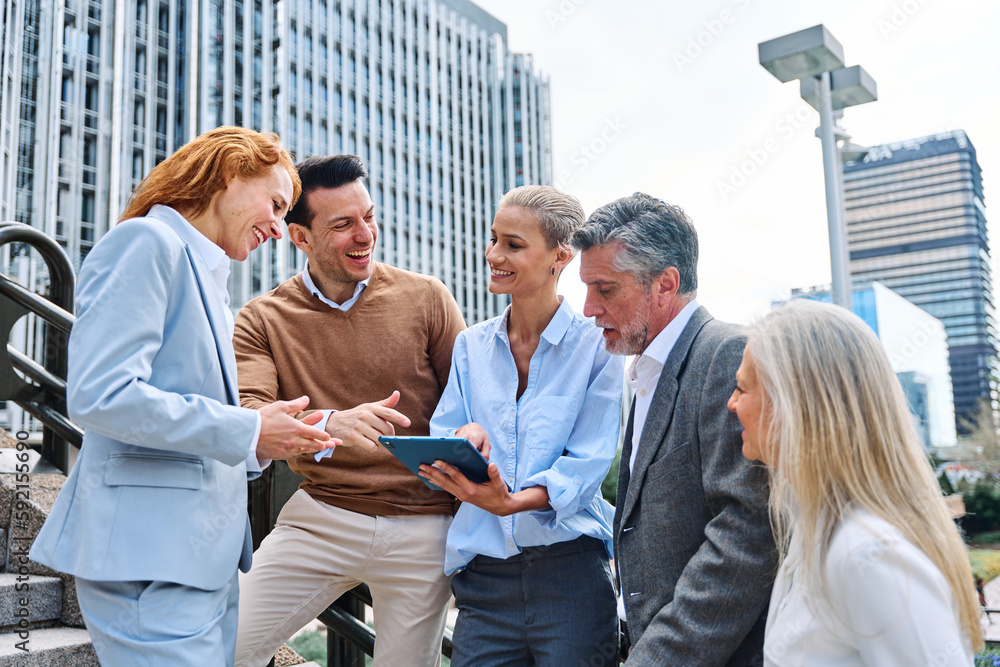 Wall mural relaxed group of business people using a tablet outdoors