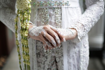the bride's hands are decorated with white henna which is very beautiful