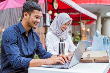 Asian male worker using a laptop sitting in the background of coworking space