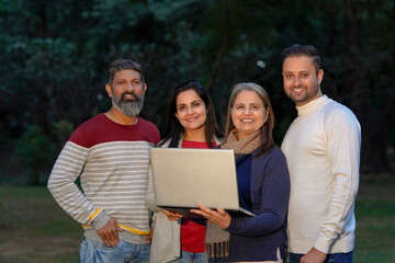 Indian or asian people in warm wear and using laptop at park