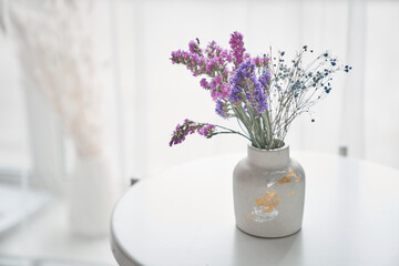 Dry flowers on the table in vase near the window. Light background with copy space. High quality photo