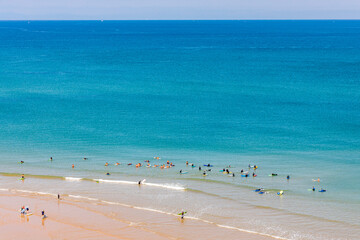 Surfers in the ocean at Cote des Basques beach in Biarritz, France on a summer day
