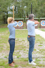 Obraz premium man and woman aiming towards archery target