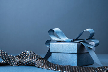 Happy Fathers Day background banner. Two blue gift boxes with ribbon bow and necktie on dark blue table. Monochrome. Gift delivery for him. Male fashion