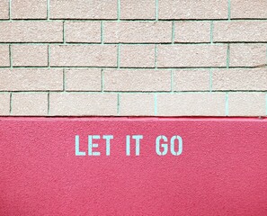 Pink rough textured  wall, with text phrase LET IT GO to remind oneself to forget or not care about...