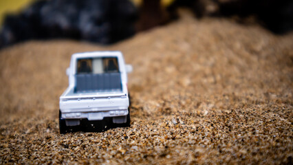 Toy car in the sand on a yellow background looks like afternoon