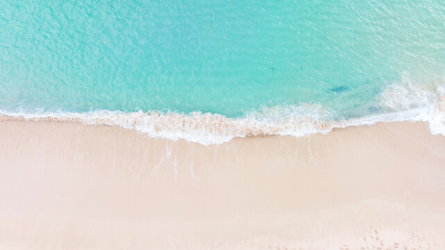 Aerial top view on nature landscape view of beautiful tropical clean sandy beach and soft blue ocean. Aerial top-down drone view.