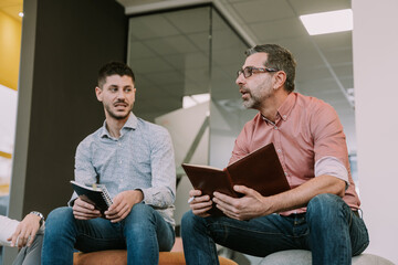 Young male person listening to his senior colleague talking