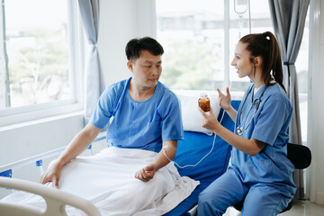 Fototapeta premium Doctor in white suit take notes while discussing and Asian elderly, man patient who lying on bed with receiving saline solution in hospital or clinic.